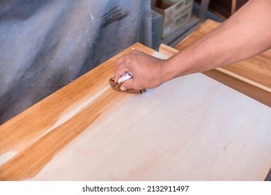 Applying Varnish To The Top Of A Shelf With A Piece Of Cloth Or Cotton Rag. At A Furniture And Woodworking Shop.