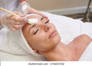 Applying white facial mask with brush in spa treatment alternative medicine