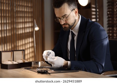 Appraiser with loupe evaluating ring at table indoors