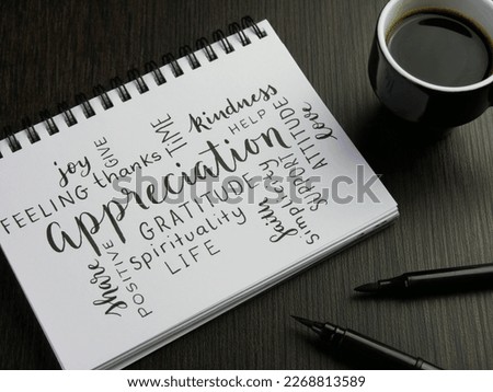 APPRECIATION handwritten word cloud in notebook with cup of espresso and pens on black wooden desk