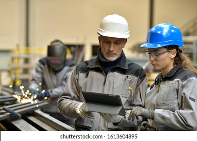 Apprentice working in steelworks plant, with instructor