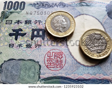 approach to japanese banknote of 1000 yen and coins of one sterling pound, background and texture