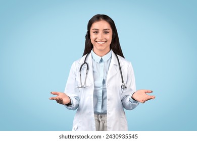 Approachable female doctor with friendly smile, open hands gesturing welcome, wearing white lab coat and stethoscope and smiling, against blue background - Powered by Shutterstock