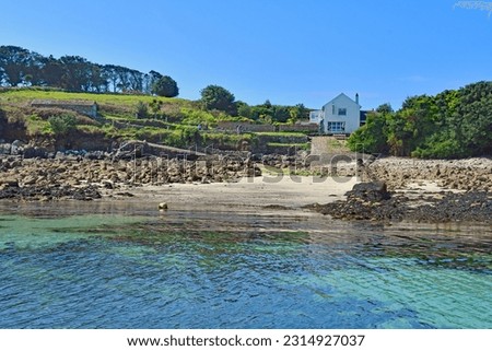 Approaching the beautiful island of St Agnes with blue sea and blue skies with the The Turk’s Head pub in the background on the exotic Isles of Scilly uk
