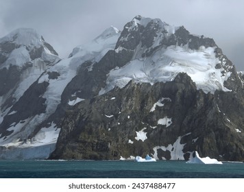    approaching the formidable mountain peaks, icebergs,  and glaciers of elephant island,  on the antarctic peninsula, on a  summer cruise on a  stormy day         - Powered by Shutterstock