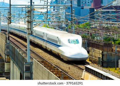 Approaching High Speed Train Shaped Like Bullet On Elevated Rails Surrounded By Wires Seen From Above Aerial View. Horizontal