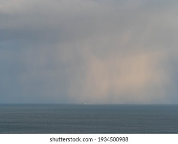 Approaching storm cloud with rain over the sea during sunrise