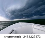 Approaching storm clouds loom over the horizon, captured from the bow of a boat on the open water.