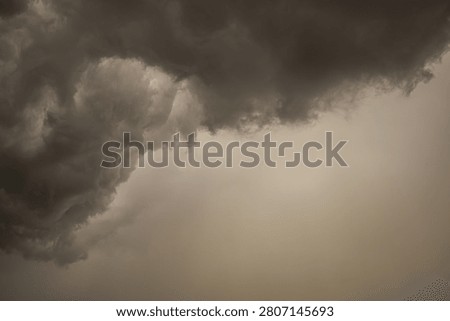Approaching Storm Clouds Over Bright Horizon. Dark storm clouds approaching over a bright horizon before heavy rainfall. The contrast between light and shadow highlights the dramatic beauty of changing weather conditions.