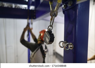 Approval pictures of stainless steel anchor point on structure pole with defocused abseiler using an inertia reel shock absorber lanyard as fall arrest fall restraint system while working at heights  - Shutterstock ID 1716548848