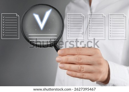 Approved documents on virtual screen. Woman holding magnifying glass with check mark inside against grey background, closeup.