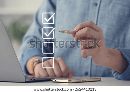 Approved. Man using laptop and checking boxes on virtual screen at table, closeup