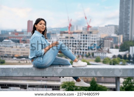 appy indian woman in a red jacket sitting in front of the city Sheffield and take photos on great summer day