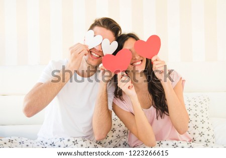 appy young couple is holding red paper hearts and smiling