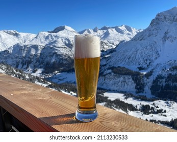 Apres Ski In The Austrian Alps. Glass Of Wheat Beer On Wooden Fence On A Sunny Day. Lech Zuers Skiing Resort, Part Of The Arlberg Skiing Area. High Quality Photo