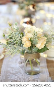 Apricot Roses In Vintage Vases On A Lace Table Runner