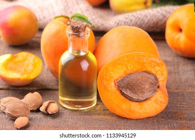 Apricot Seed Oil Next To Fresh Apricots On A Brown Background