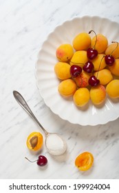 Apricots and cherries on a plate on a marble table - Shutterstock ID 199924004