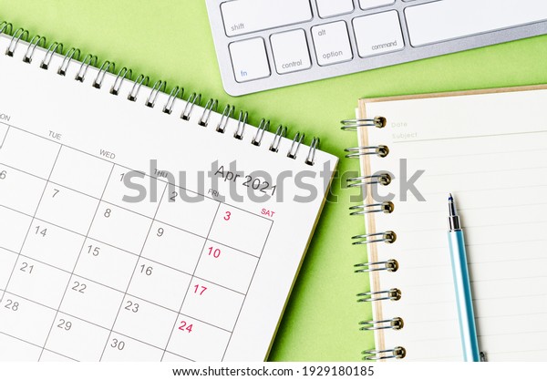 April 2021 calendar with note book on green\
color background.