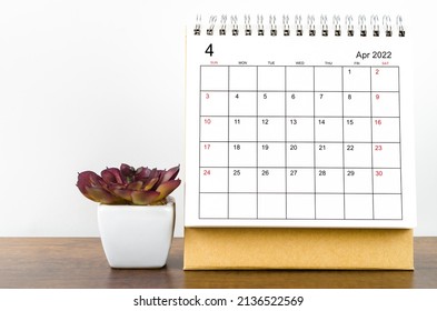 The April 2022 desk calendar with plant on wooden table. - Shutterstock ID 2136522569