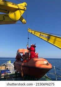 April, 2022. The Process Of Lowering A Lifeboat Or Rescue Boat Into The Water To Perform A Man Overboard Drill And Abandon Ship Drill. The Crew Of The Ship Are Working Together To Steer The Lifeboat 