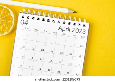 April 2023 Monthly desk calendar for 2023 year with wooden pencil on yellow background.