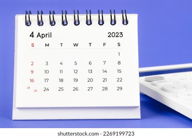 April 2023 Monthly desk calendar for 2023 year with calculator on purple background.