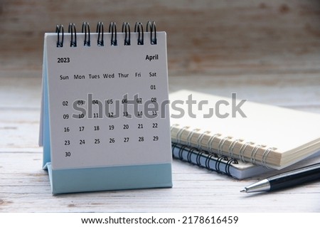 April 2023 white desk calendar on wooden table with notepad and pen background. New year concept and copy space Foto d'archivio © 