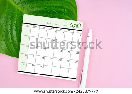 April 2024 calendar page and fresh green leaf with water drops on pink color background.