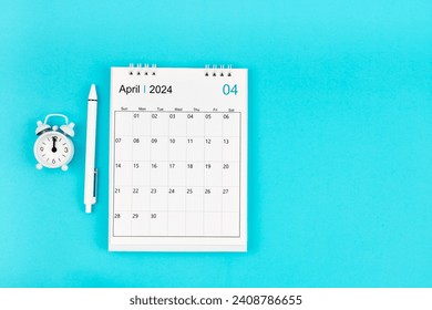 April 2024, Monthly desk calendar for 2024 year and pen with alarm clock on blue color background.