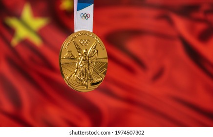 April 25, 2021 Tokyo, Japan. Gold medal of the XXXII Summer Olympic Games 2020 in Tokyo on the background of the flag of China.