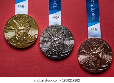 April 25, 2021 Tokyo, Japan. Gold, Silver And Bronze Medals Of The XXXII Summer Olympic Games In Tokyo On A Red Background.