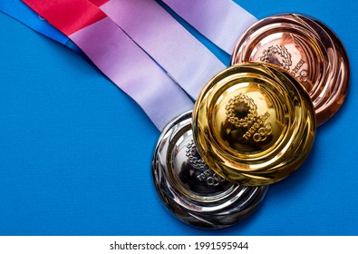 April 25, 2021 Tokyo, Japan. Gold, Silver And Bronze Medals Of The XXXII Summer Olympic Games In Tokyo On A Blue Background.