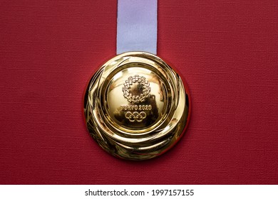 April 25, 2021 Tokyo, Japan. Gold Medal Of The XXXII Summer Olympic Games In Tokyo On A Red Background.