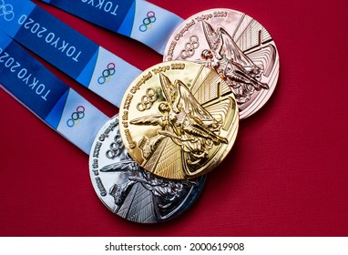 April 25, 2021 Tokyo, Japan. Gold, silver and bronze medals of the XXXII Summer Olympic Games in Tokyo on a red background.