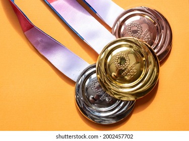 April 25, 2021 Tokyo, Japan. Gold, Silver And Bronze Medals Of The XXXII Summer Olympic Games In Tokyo On A Yellow Background.