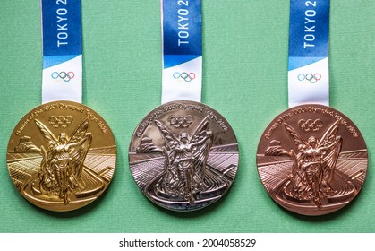 April 25, 2021 Tokyo, Japan. Gold, Silver And Bronze Medals Of The XXXII Summer Olympic Games In Tokyo On A Green Background.