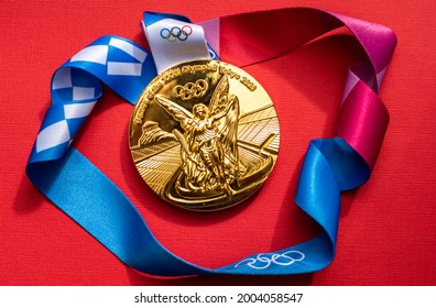 April 25, 2021 Tokyo, Japan. Gold Medal Of The XXXII Summer Olympic Games In Tokyo On A Red Background.