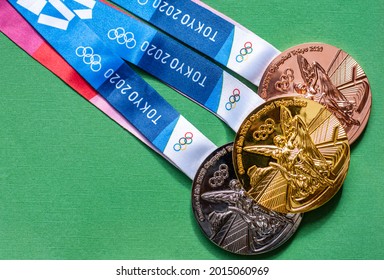 April 25, 2021 Tokyo, Japan. Gold, Silver And Bronze Medals Of The XXXII Summer Olympic Games In Tokyo On A Green Background.