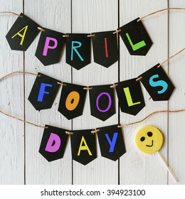 April Fools Day Black Banner Colorful Lettering On White Barn Wood Rustic Planks Background. Holiday Greeting Postcard.