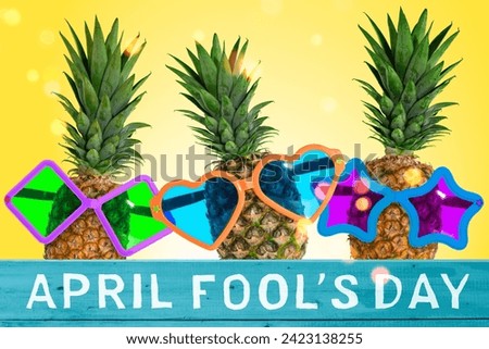 April Fools' Day celebrated on April 1 concept, Ripe pineapples wearing funny color sunglasses on a brigh background with decorative lettering