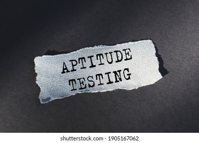 APTITUDE TESTING - text on torn paper on dark desk in sunlight.