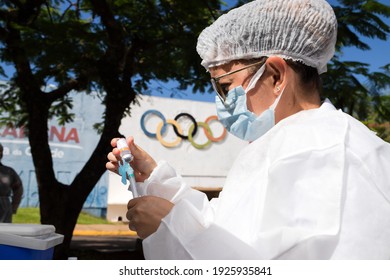 Apucarana, Paraná, Brazil - February 17, 2021 - Health Professional Prepares Syringe With Coronavirus Vaccine (COVID-19) In The Apucarana Sports Gymnasium, At The Background Of The Olympics.