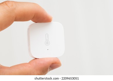 Aqara Smart Home Temperature Sensor in mans hand on the white background. 