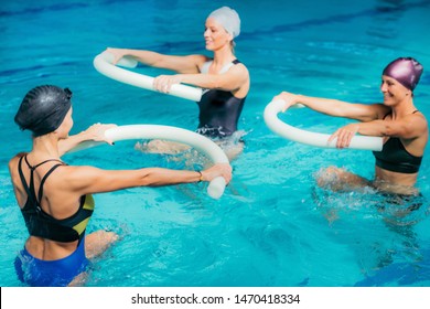Aqua Aerobic Training mit Wasser-Fitness-Ausrüstung. Frauen, die mit Schwimmnudeln trainieren.