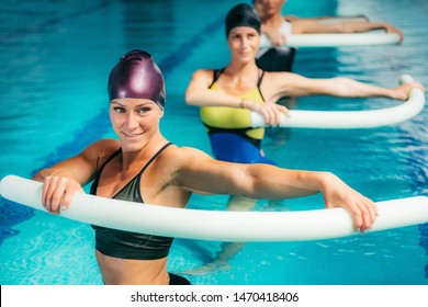 Aqua Aerobic Training with Water Fitness Equipment. Women Training with Swimming Noodles.