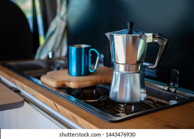 Aqua Bialetti stovetop coffee maker and mug, on a van gas cooker