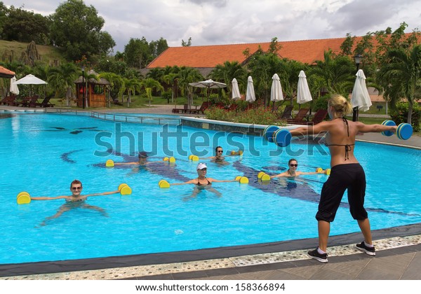 Aqua Gym: aerobics /\
fitness instructor in front of a group of people in the water\
performing exercises.