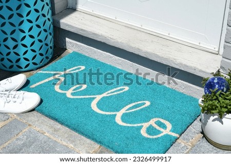 Aqua teal hello welcome mat on a front porch in the summer