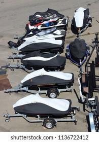 A Lot Of Aquabikes On Boat Trailers On Asphalt Parking In The Marina In The Summer - Storage Of Ships On The Shore, Vertical Frame, Top View